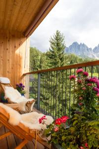 une terrasse couverte avec un banc et des fleurs sur un balcon dans l'établissement Hotel Tyrol, à Funes