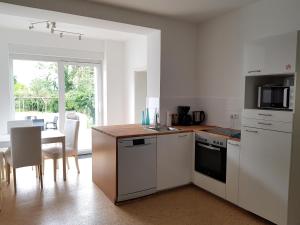 une cuisine avec des appareils électroménagers blancs et une table avec des chaises dans l'établissement Haus Roy, à Zülpich