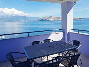 a table and chairs on a balcony with a view of the water at Apartments Lavanda - Kricin in Baška