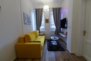 Apartman Royal في سلافونسكي برود: غرفة معيشة بها أريكة صفراء وتلفزيون