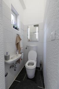 a white bathroom with a toilet and a sink at Apartman Royal in Slavonski Brod