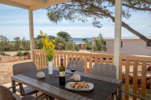 a table with a bottle of wine and a plate of bread at Mobile Homes at Camping Ugljan Resort in Ugljan