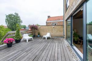 eine Holzterrasse mit zwei weißen Stühlen und Pflanzen in der Unterkunft Vintage Duplex in Bruges in Brügge