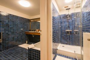 a blue tiled bathroom with a shower and a tub at Vintage Duplex in Bruges in Bruges