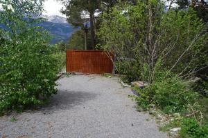 un camino de grava con una valla de madera en una colina en Chalet Plaisir- la nature, en Uvernet