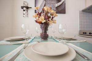 a table with plates and glasses and a vase of flowers at Casa de Campo 1 in Almyrida +9 photos
