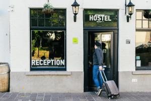 un homme tirant une valise de la porte d'un hôtel dans l'établissement St Christopher's Inn Hostel at The Bauhaus, à Bruges