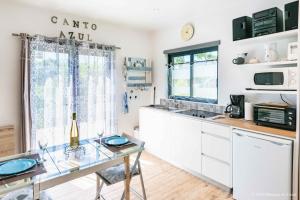 a kitchen with white cabinets and a glass table at Gîte CANTO AZUL in Casal da Carreira