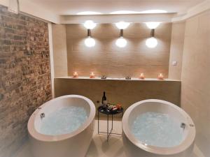 two large tubs in a bathroom with candles and a table at Dvůr Stráň in Karlovy Vary