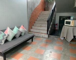 a living room with a couch and stairs with a microwave at Isayarada Apartment in Thalang