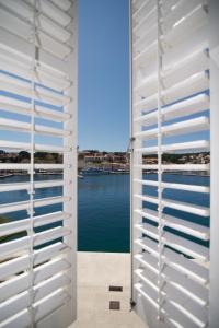 a view of the water from a window with white shutters at Apartments and Rooms Jospino in Mali Lošinj