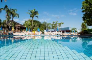 une grande piscine avec des chaises blanches et des palmiers dans l'établissement Hotel Estância Barra Bonita, à Barra Bonita