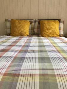 a bed with a plaid blanket and two pillows at Northorpe in Hornsea