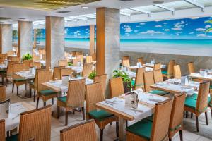 トッサ・デ・マールにあるGHT Oasis Tossa & Spaのテーブルと椅子、ビーチの壁画のあるレストラン