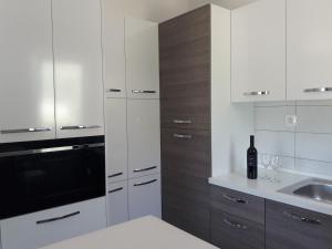 een keuken met witte kasten, een wastafel en een fles wijn bij Apartment Jelena in Podstrana
