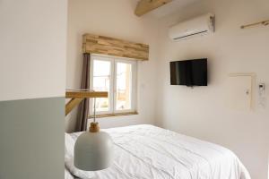 a white bedroom with a bed and a window at Le Chalet du Papa in Gruissan