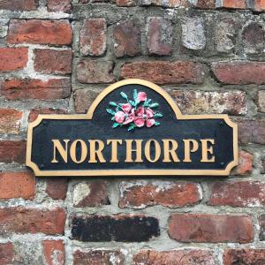 a sign on a brick wall with the wordsnorride at Northorpe in Hornsea