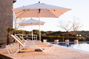 zwei Stühle und ein Regenschirm neben einem Pool in der Unterkunft Hotel Es Blau Des Nord in Colònia de Sant Pere