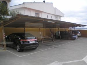 une voiture garée sous un garage avec un bâtiment dans l'établissement Hostal Real, à Plasence