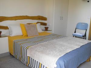 um quarto com uma cama grande e uma cadeira azul em A casa do Moinho em Pedrógão Pequeno