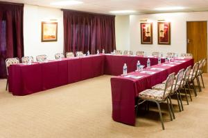 una mesa larga en una habitación con mesas y sillas púrpuras en Willows Garden Hotel Potchefstroom, en Potchefstroom