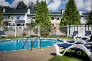 a swimming pool with chairs next to a building at Motel Le JoliBourg in Saint-Sauveur-des-Monts