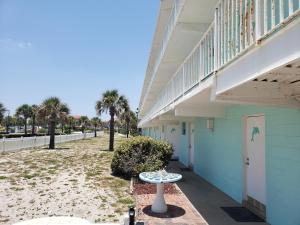 uma mesa ao lado de um edifício com uma varanda em SeaScape Inn - Daytona Beach Shores em Daytona Beach