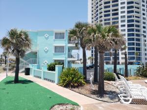 un edificio azul con palmeras y sillas blancas en SeaScape Inn - Daytona Beach Shores en Daytona Beach