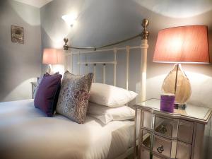 a bedroom with a bed with a lamp and pillows at Century House in Moreton in Marsh