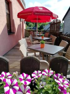 patio ze stołami i krzesłami oraz czerwonym parasolem w obiekcie Gasthaus Goldner Löwe w mieście Friesau