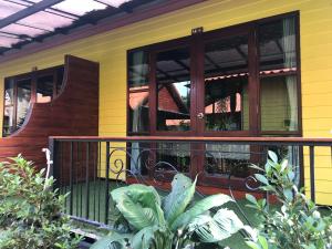 a yellow house with a wooden door and balcony at Ricci House Resort in Ko Lipe