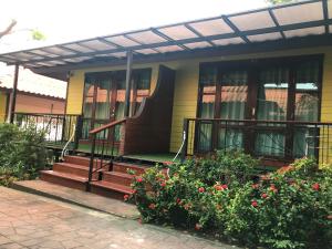 a yellow house with a porch and some flowers at Ricci House Resort in Ko Lipe