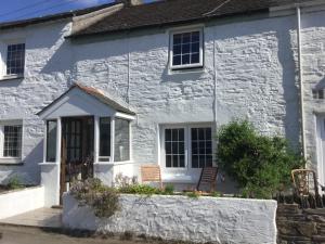 a white cottage with a white stone facade at Jasmine Cottage in Lerryn