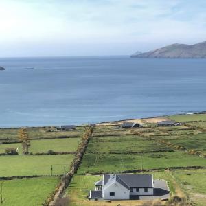 a house in a field next to a body of water at Skellig View House in Waterville