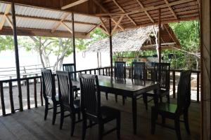 a dining room with a table and chairs on a deck at Tanjung Kalemo Resort in Batudaka