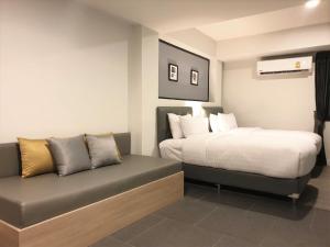 um quarto de hotel com uma cama e um sofá em Mayson Place Hotel em Ban Phraek Sa