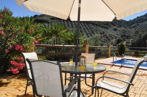 uma mesa e cadeiras com um guarda-sol num pátio em Cortijo Rural Las Nogueras em Cortijada Los Chorreros