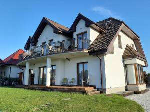 a white house with a balcony and lawn at Dom gościnny u Chudego in Rewal