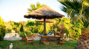 a table and chairs under a straw umbrella at Villa Swan in Lefkada