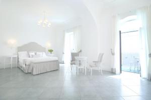 a white bedroom with a bed and a table and chairs at Hotel Marincanto in Positano