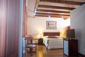 a bedroom with a bed and a desk with a tv at Posada del Frayle Bentos in Fray Bentos