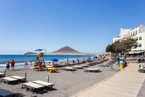 a beach with a bunch of people on the beach at The wave house El Médano in El Médano