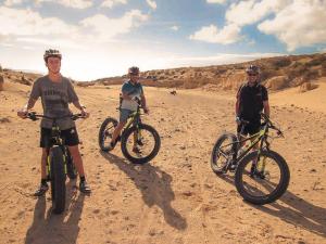 Drie mannen staan op fietsen in de woestijn. bij Studio - Agua - Surf & Yoga Villa in La Pared
