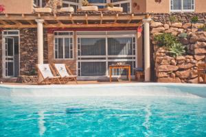 een zwembad met twee stoelen naast een huis bij Studio - Agua - Surf & Yoga Villa in La Pared
