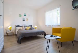 1 dormitorio con 1 cama y 1 silla amarilla en Apartments Zambarlin, en Komiža