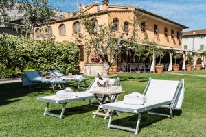 un grupo de mesas de picnic frente a un edificio en Giardino della Pieve Relais, en Cascina