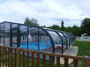 a swimming pool with a canopy in a park at Camping La Pindière in Héric