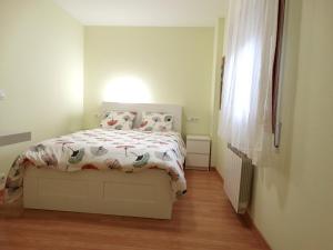 a small bedroom with a bed with a white comforter at Apartamento del Rosario in Corella