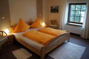 ein Schlafzimmer mit einem Bett mit orangefarbener Bettwäsche und einem Fenster in der Unterkunft Pension Loni Theisen in Kelberg
