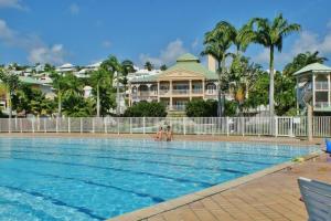 una piscina in un resort con persone in acqua di Jolie studio meublé avec petite vue mer a Saint-François